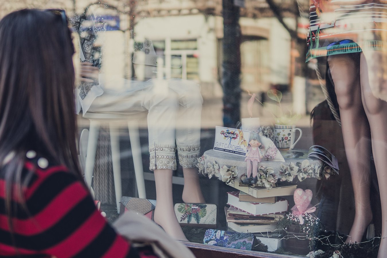 Una donna guarda una vetrina con articoli da regalo e vestiti.