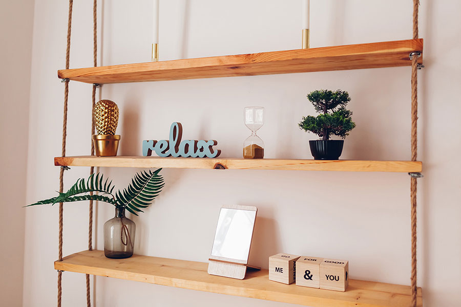 Das Bild zeigt ein hängendes Holzregal, das mit Seilen an der Decke befestigt ist. Es besteht aus drei naturbelassenen Holzbrettern – DIY-Ideen für Upcycling-Materialien