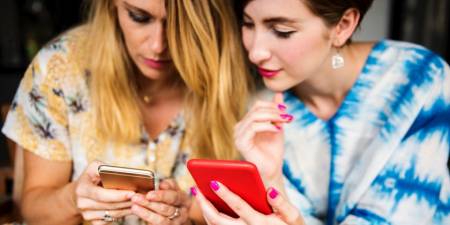 Two women looking at their mobile phones.