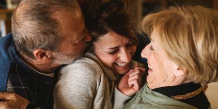 Parents hugging and kissing their daughter, which symbolically represents long-term investment and investing in the future.